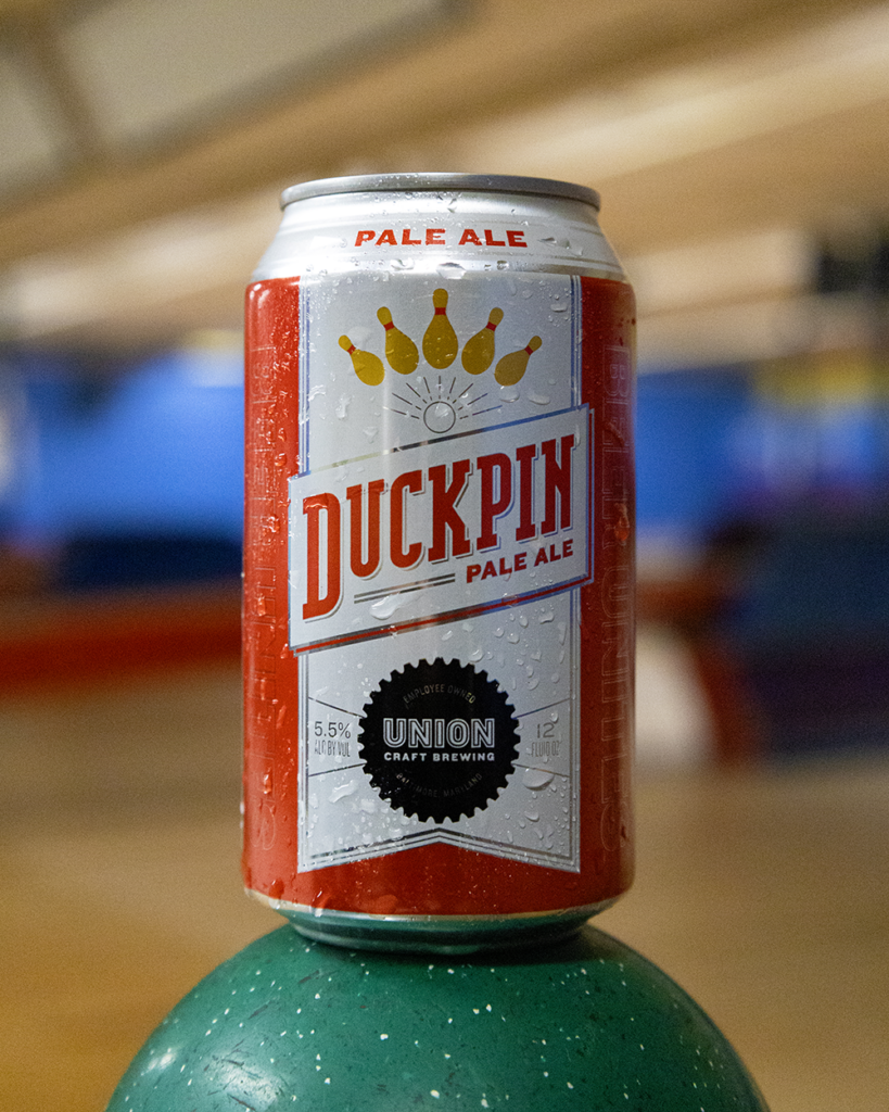 A can of Union Craft Brewing Duckpin Pale Ale resting on top of a green duckpin bowling ball.