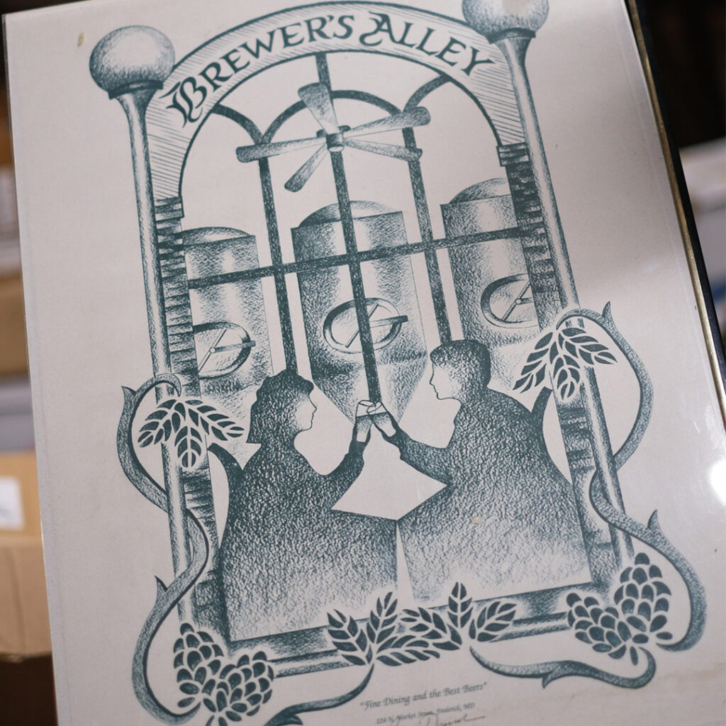A framed print for Brewer’s Alley showing a silhouette of two people clinking glasses in front of brewery tanks, with the tagline “Fine Dining and the Best Beers” and the Frederick, Maryland address at the bottom.