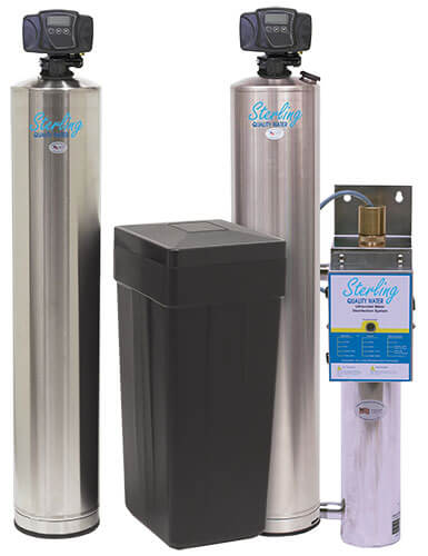 Two tall, cylindrical stainless steel water filtration tanks flanking a black rectangular salt tank, with a smaller vertical ultraviolet water purification unit on the right.